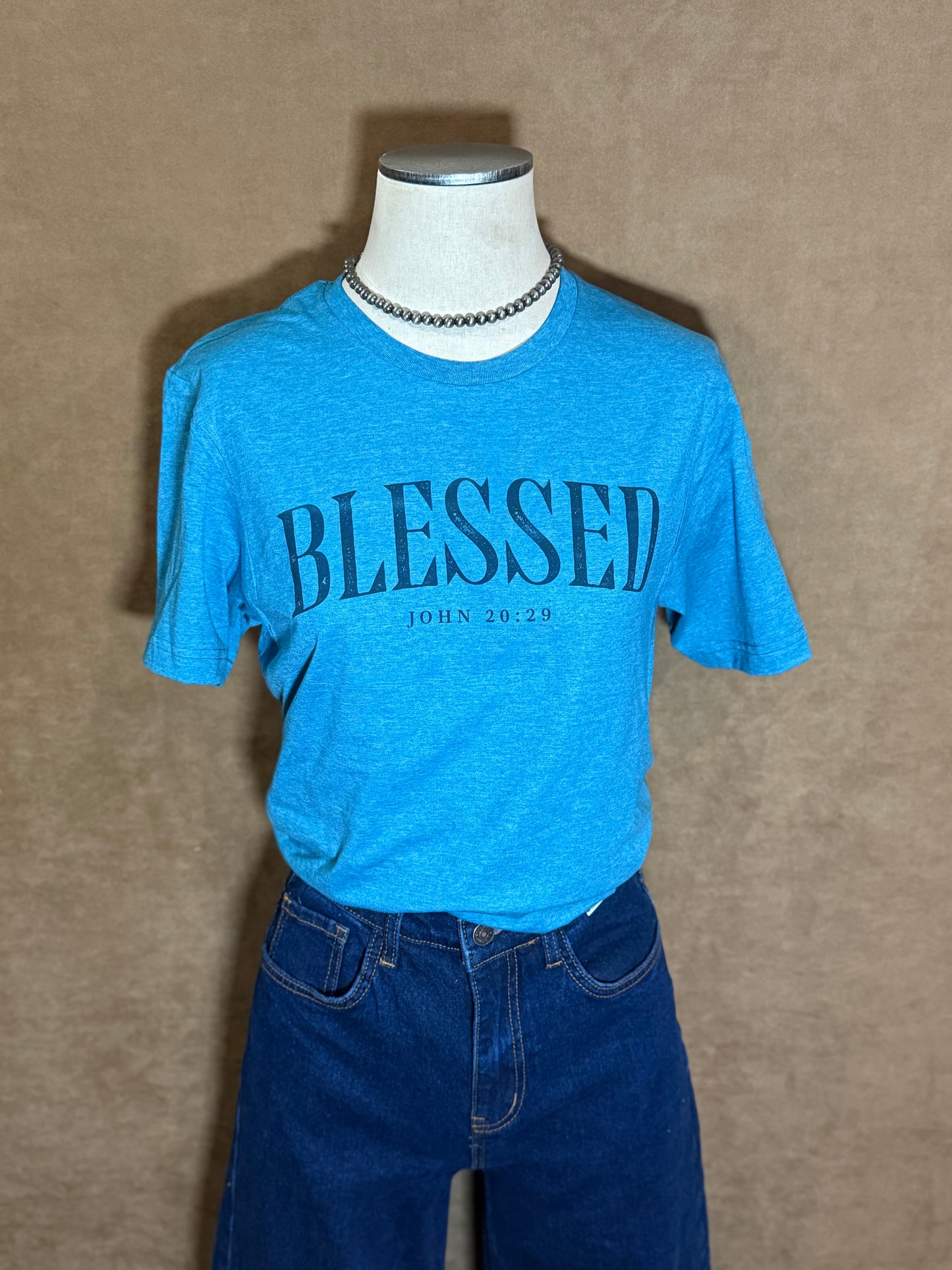 Mannequin wearing a blue t-shirt with 'BLESSED' text on a beige background