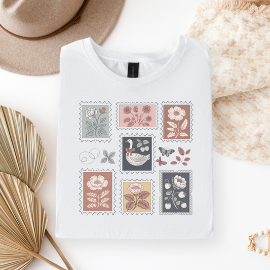 White t-shirt with floral and nature-themed stamps on a neutral background